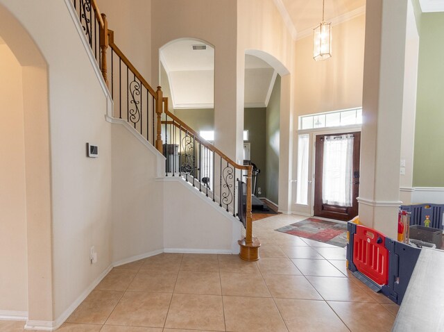 tiled foyer with a high ceiling and ornamental molding