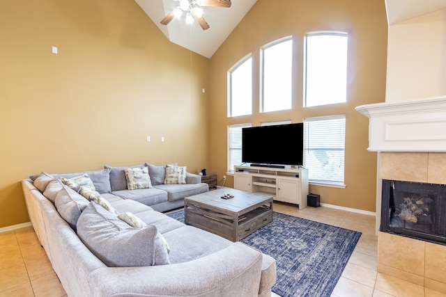 living room with a tile fireplace, high vaulted ceiling, light tile patterned flooring, and ceiling fan