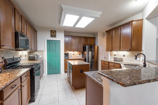 kitchen featuring a kitchen island, sink, tasteful backsplash, and black appliances