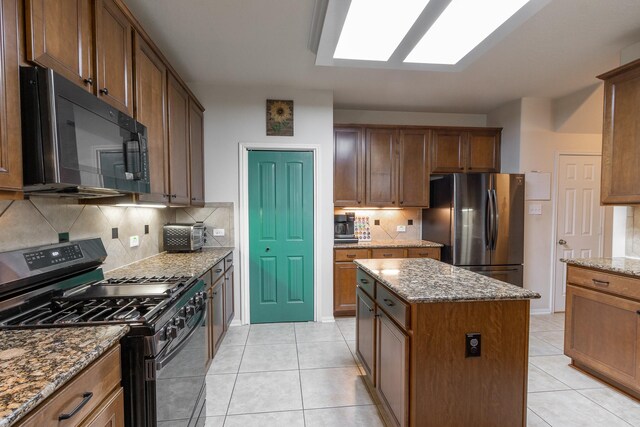 kitchen with range with gas cooktop, a center island, stainless steel refrigerator, light tile patterned floors, and backsplash