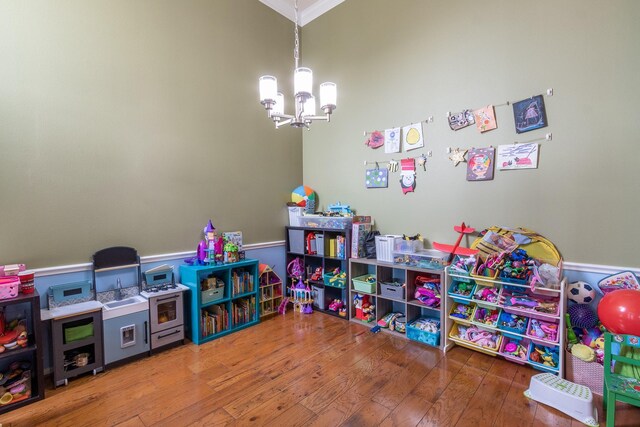 rec room with hardwood / wood-style flooring, crown molding, and a chandelier