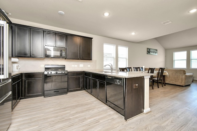 kitchen with black appliances, sink, backsplash, light stone counters, and kitchen peninsula