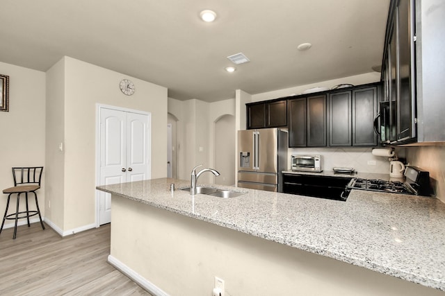 kitchen featuring sink, range, light stone counters, tasteful backsplash, and high quality fridge