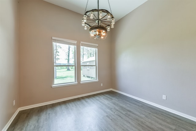 empty room featuring an inviting chandelier and dark wood-type flooring