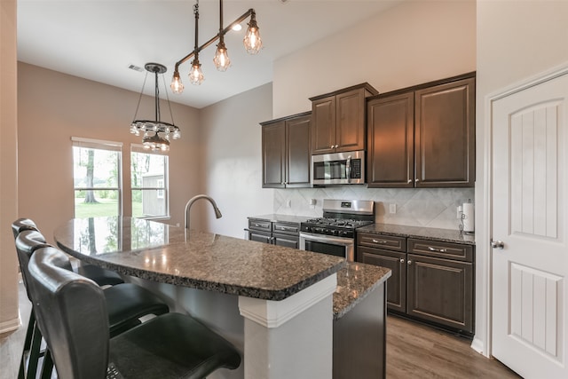 kitchen with pendant lighting, a breakfast bar, an island with sink, and appliances with stainless steel finishes