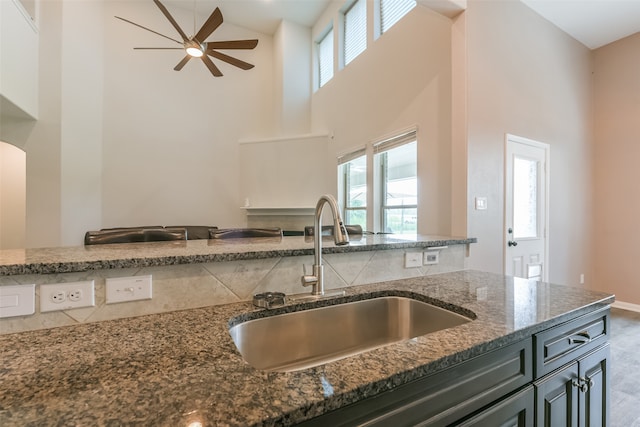 kitchen featuring dark stone countertops, a wealth of natural light, sink, and a high ceiling