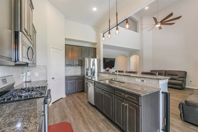 kitchen featuring high vaulted ceiling, a center island with sink, sink, hardwood / wood-style flooring, and appliances with stainless steel finishes