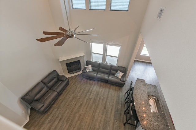 living room featuring ceiling fan, dark hardwood / wood-style flooring, and a towering ceiling