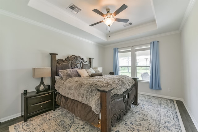 bedroom with ceiling fan, wood-type flooring, crown molding, and a tray ceiling