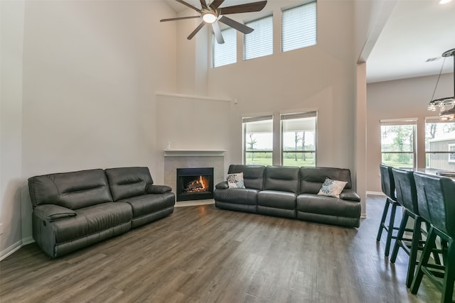 living room featuring a wealth of natural light, a towering ceiling, dark hardwood / wood-style floors, and ceiling fan