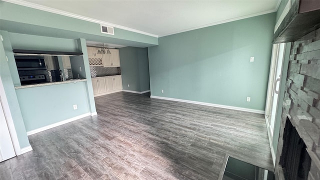 unfurnished living room featuring ornamental molding and dark wood-type flooring