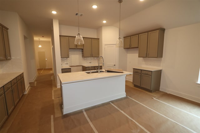 kitchen with tasteful backsplash, a kitchen island with sink, sink, and hanging light fixtures