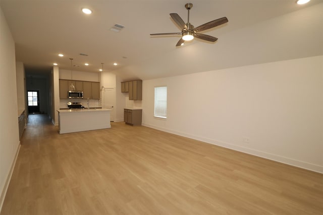 unfurnished living room featuring sink, vaulted ceiling, ceiling fan, and light wood-type flooring