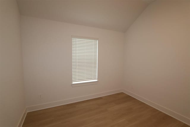 unfurnished room with vaulted ceiling and light wood-type flooring