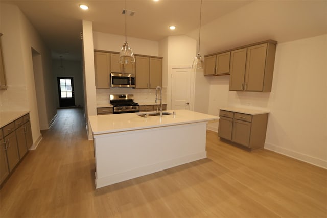 kitchen with stainless steel appliances, decorative light fixtures, light hardwood / wood-style floors, and sink