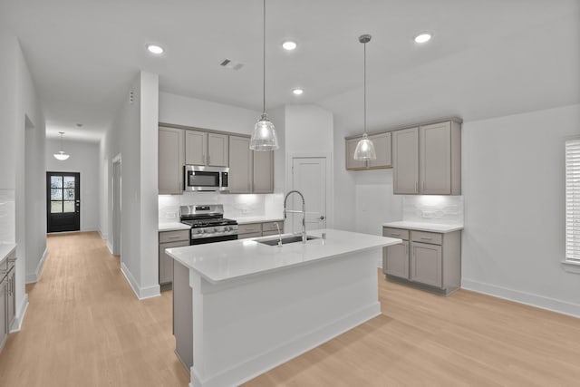 kitchen with visible vents, an island with sink, stainless steel appliances, light countertops, and a sink