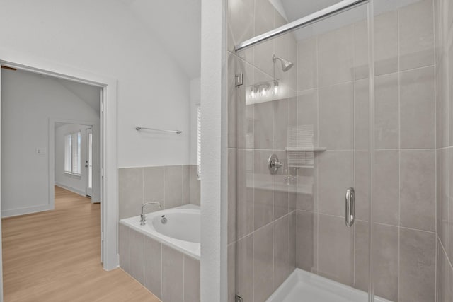 bathroom with a garden tub, vaulted ceiling, a shower stall, and wood finished floors