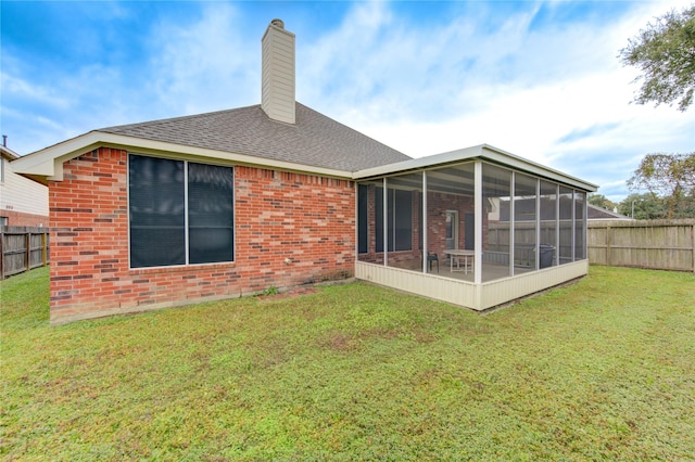 rear view of property featuring a sunroom and a yard