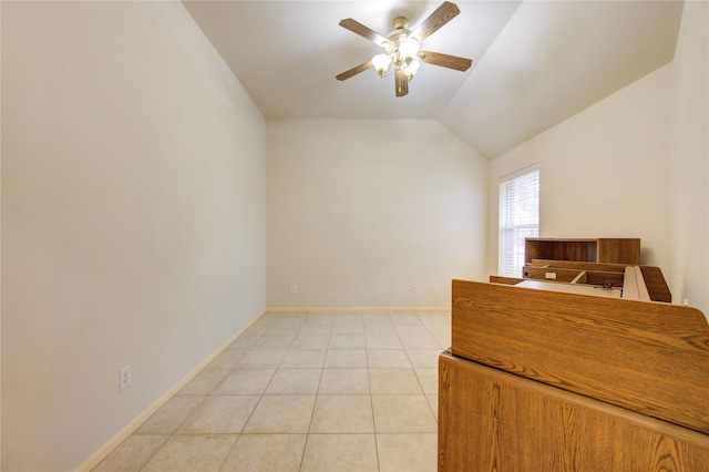 spare room with ceiling fan, lofted ceiling, and light tile patterned flooring