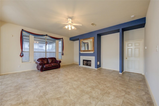 unfurnished room with a tiled fireplace and ceiling fan