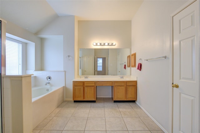 bathroom featuring tile patterned floors, tiled tub, vanity, and lofted ceiling