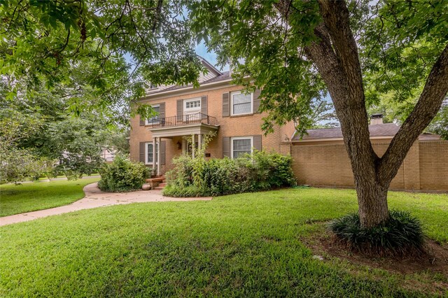 colonial home with a balcony and a front lawn