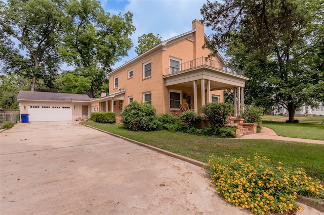 view of front of property with a garage, a balcony, covered porch, and a front yard