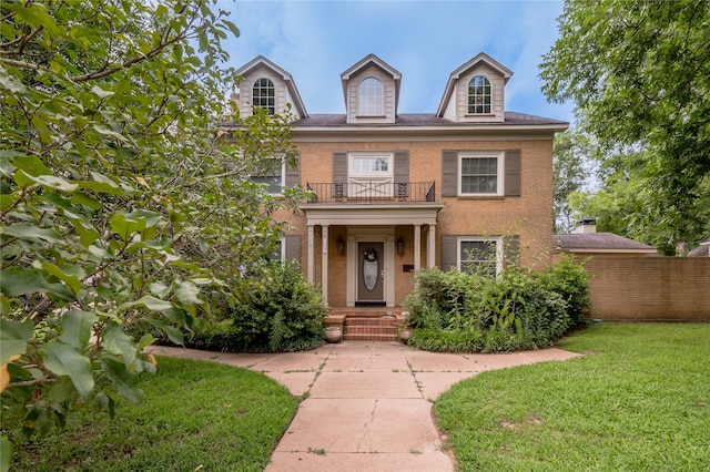 view of front facade featuring a balcony and a front yard