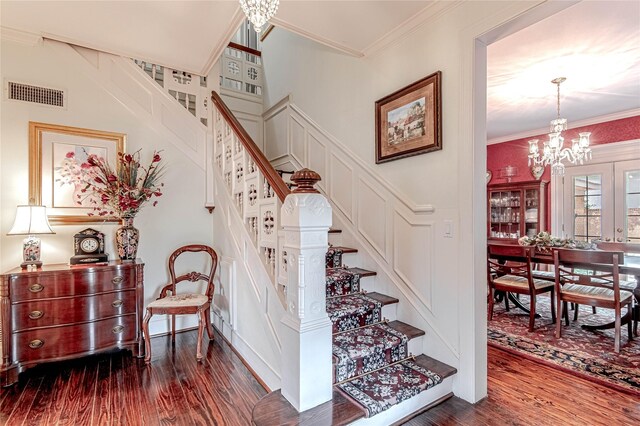 stairway with an inviting chandelier, dark hardwood / wood-style floors, and ornamental molding