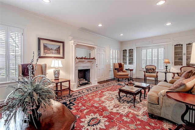 living room featuring ornamental molding, a wealth of natural light, a fireplace, and hardwood / wood-style flooring