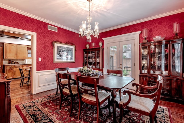 dining room with a chandelier, french doors, ornamental molding, and hardwood / wood-style floors