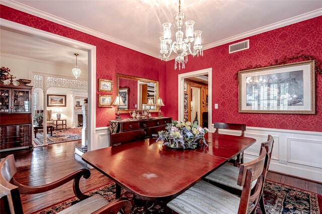 dining space featuring ornamental molding, hardwood / wood-style flooring, and a chandelier