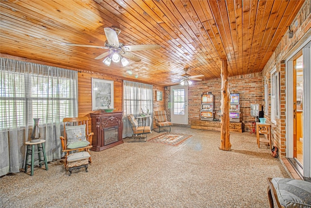 sitting room with wood ceiling, a wood stove, brick wall, and ceiling fan