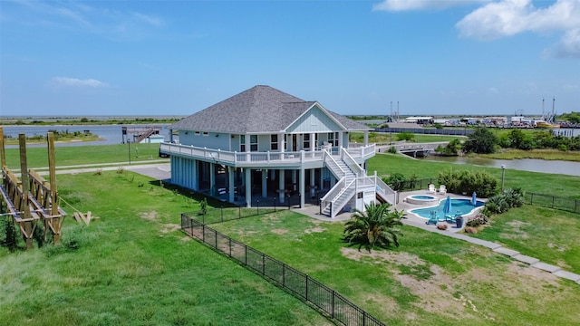 rear view of property featuring a fenced in pool, a yard, a water view, and a patio