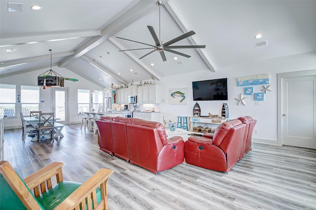 living room featuring ceiling fan, light hardwood / wood-style floors, and vaulted ceiling with beams