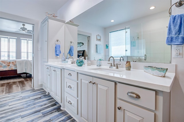 bathroom with ceiling fan, vanity, a shower with door, and hardwood / wood-style flooring