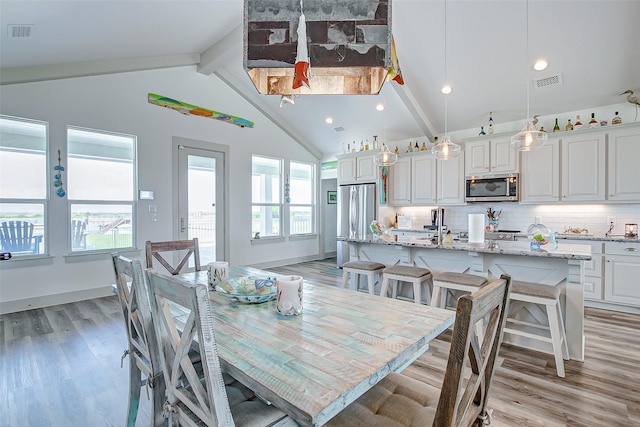 dining area with lofted ceiling with beams and light hardwood / wood-style flooring