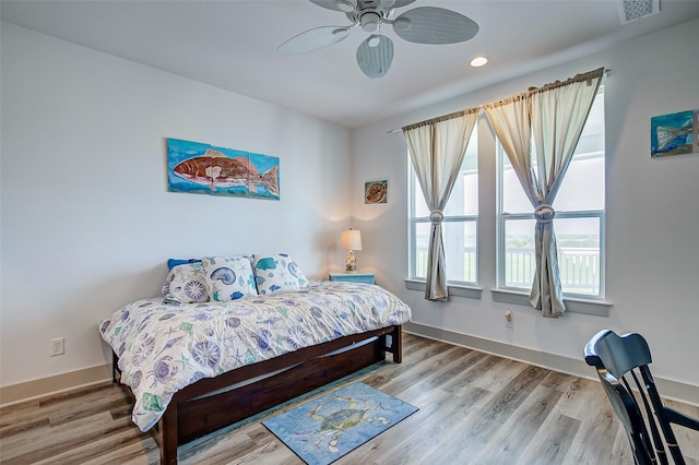 bedroom featuring ceiling fan, multiple windows, and light hardwood / wood-style floors