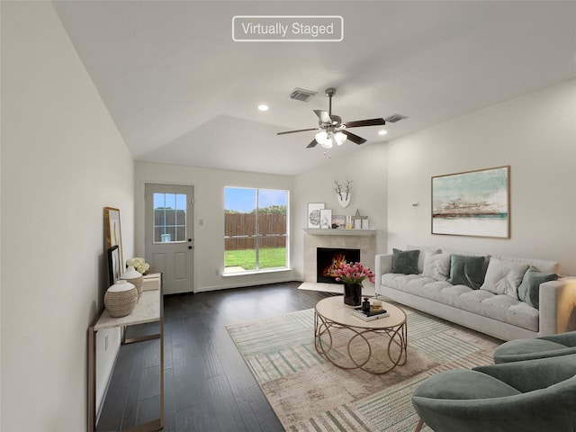 living room featuring a tile fireplace, dark hardwood / wood-style flooring, ceiling fan, and vaulted ceiling