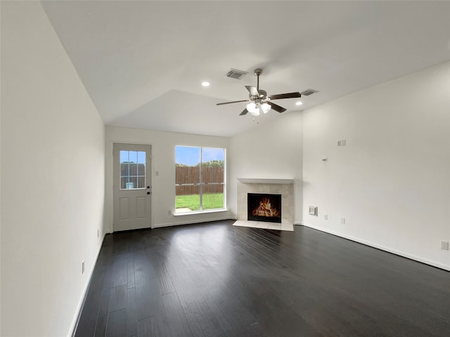 unfurnished living room featuring dark hardwood / wood-style floors, a tiled fireplace, vaulted ceiling, and ceiling fan