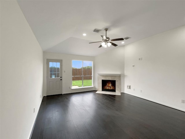 unfurnished living room featuring ceiling fan, dark hardwood / wood-style floors, a tiled fireplace, and vaulted ceiling