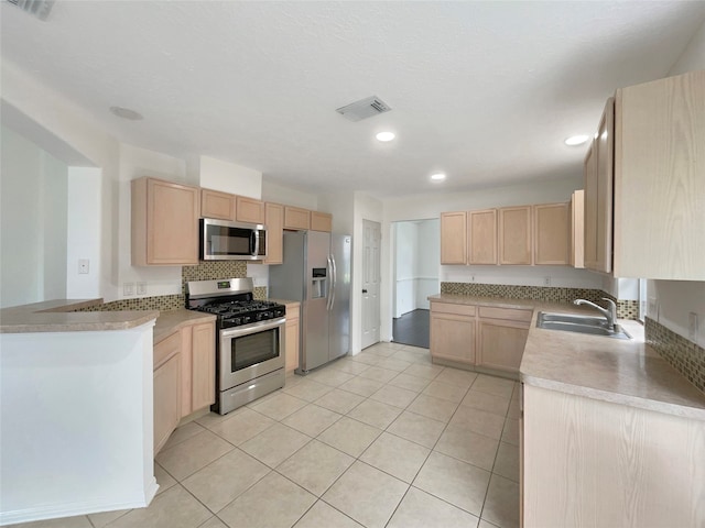 kitchen with appliances with stainless steel finishes, light tile patterned floors, sink, and light brown cabinets