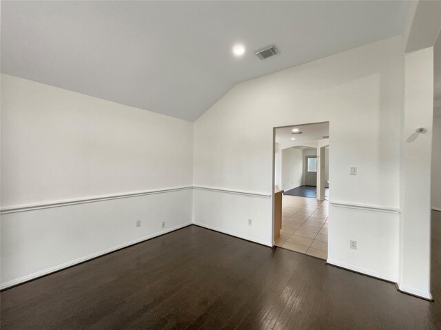 empty room featuring wood-type flooring and vaulted ceiling