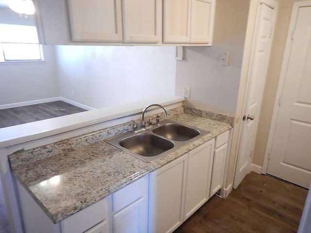 kitchen featuring sink, dark wood-type flooring, light stone counters, and white cabinetry