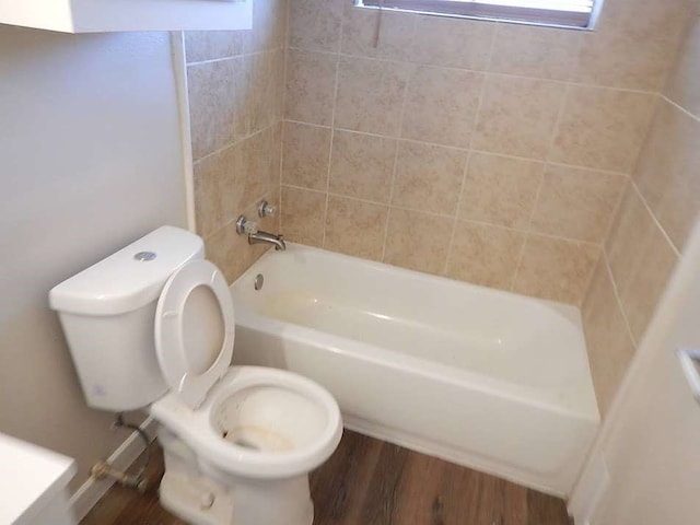 bathroom with tiled shower / bath, toilet, and wood-type flooring