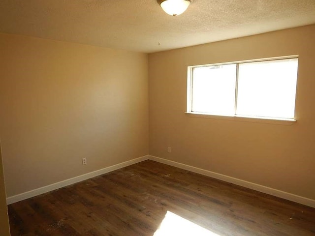 unfurnished room with a textured ceiling and dark hardwood / wood-style floors