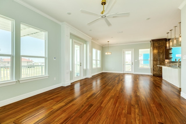 unfurnished living room with ceiling fan, a wealth of natural light, dark hardwood / wood-style floors, and crown molding