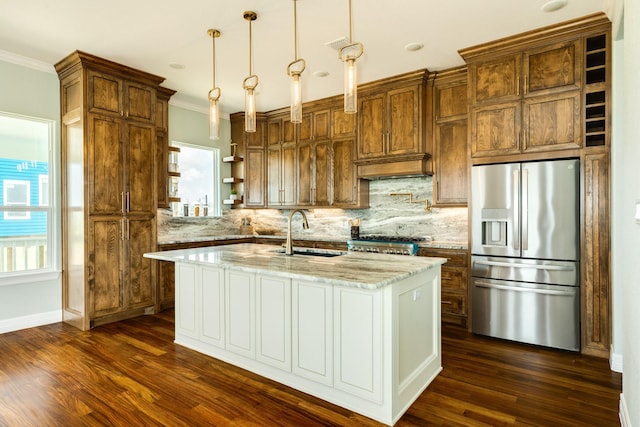 kitchen featuring light stone countertops, pendant lighting, sink, stainless steel fridge, and a center island with sink