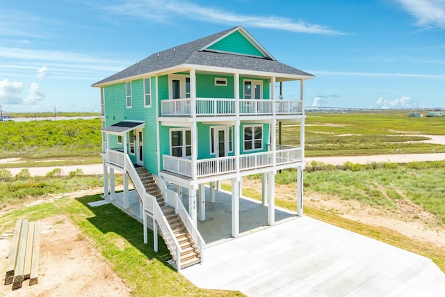 back of property with a balcony, a rural view, a porch, and a carport