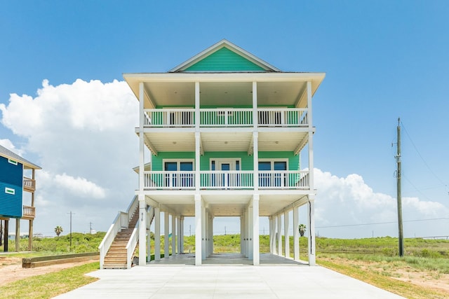 coastal inspired home featuring covered porch, a carport, and a balcony